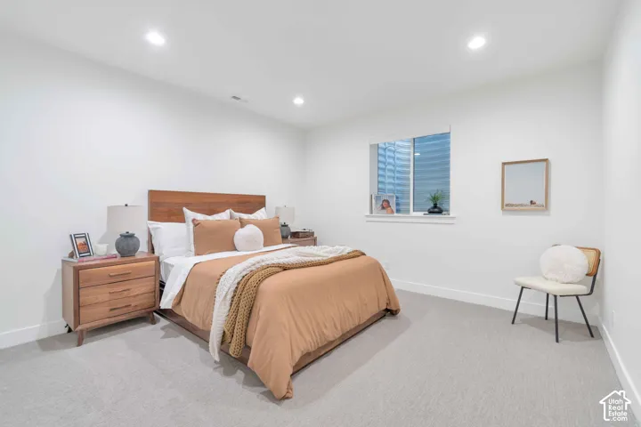 Neutral interior featuring high-pile wall-to-wall carpeting, recessed ceiling lighting, and a single-pane sliding window with an egress well