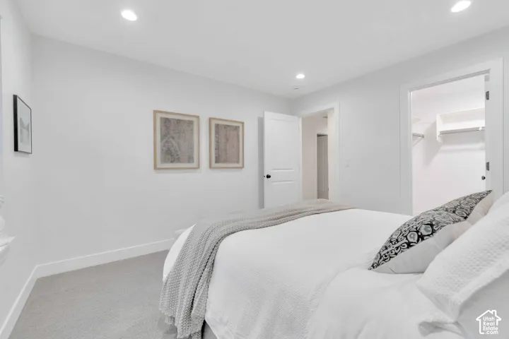 Neutral wall palette with recessed lighting, carpeted flooring, and a walk-in closet featuring built-in shelving