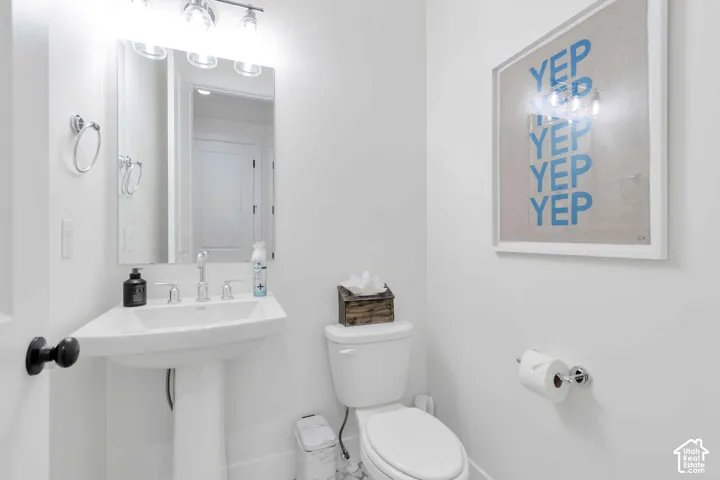 Pedestal sink with chrome widespread faucet, polished plate mirror, and three-light vanity fixture