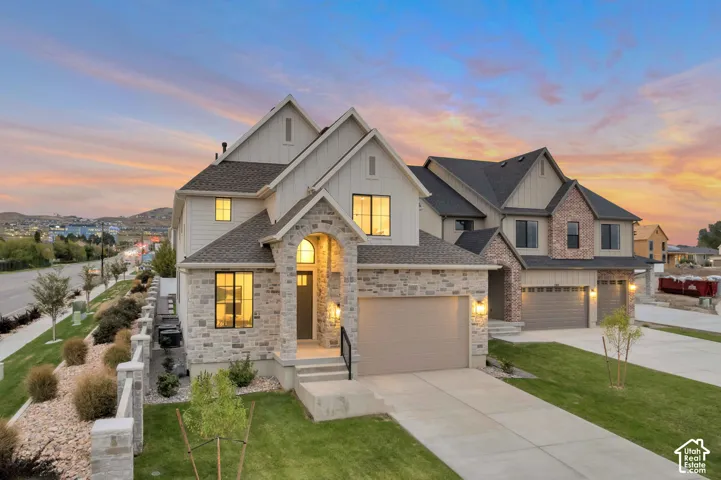 Multi-story exterior featuring a combination of stone veneer and vertical siding, covered entryway with an arched stone surround, multiple peaked rooflines, and multi-car garages