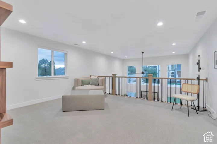 Open loft area featuring neutral carpeting, recessed ceiling lighting, a ceiling fan, and metal balusters with wooden handrails
