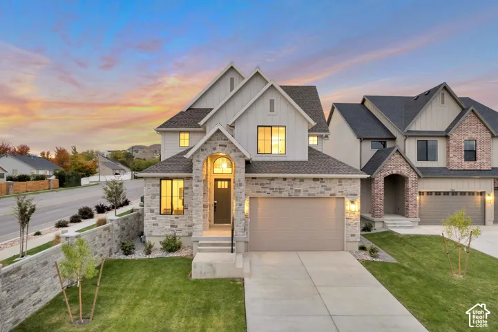 Multi-gabled exterior featuring board-and-batten siding, natural stone veneer accents, an arched entryway, and an integrated two-car garage