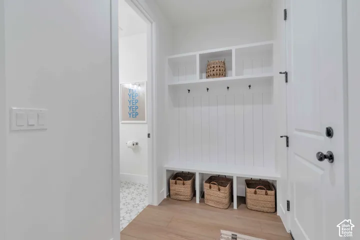 Built-in mudroom bench featuring vertical shiplap paneling, upper storage cubbies, and matte black hardware