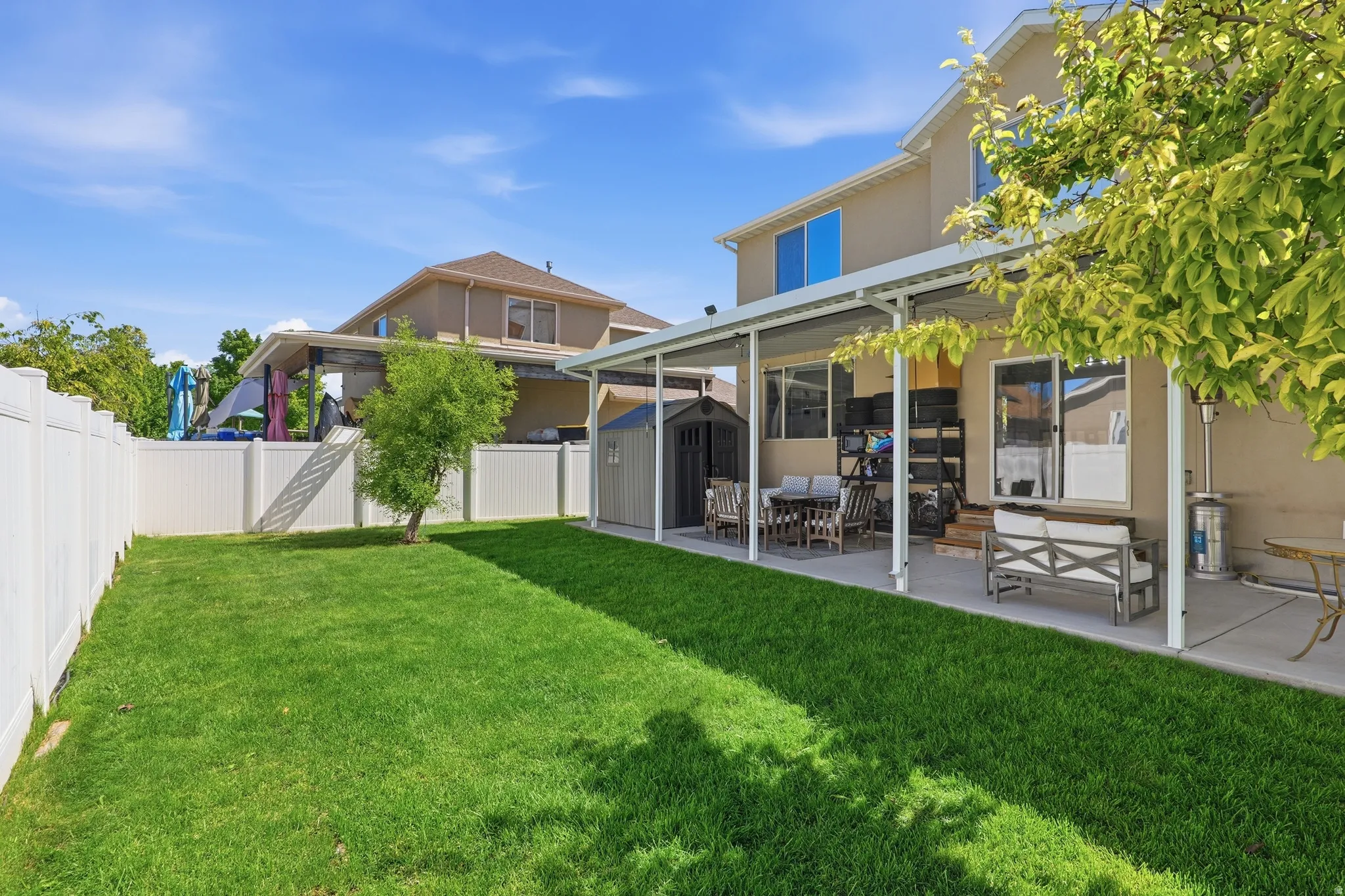Expansive backyard featuring a manicured lawn, full vinyl privacy fencing, and a covered patio structure