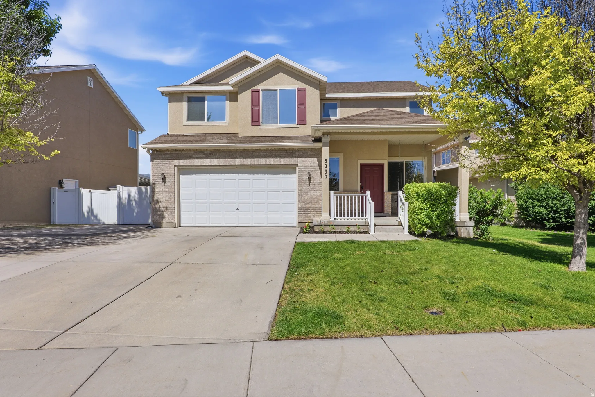 Two-story residence featuring a two-car garage, concrete driveway, and a front lawn