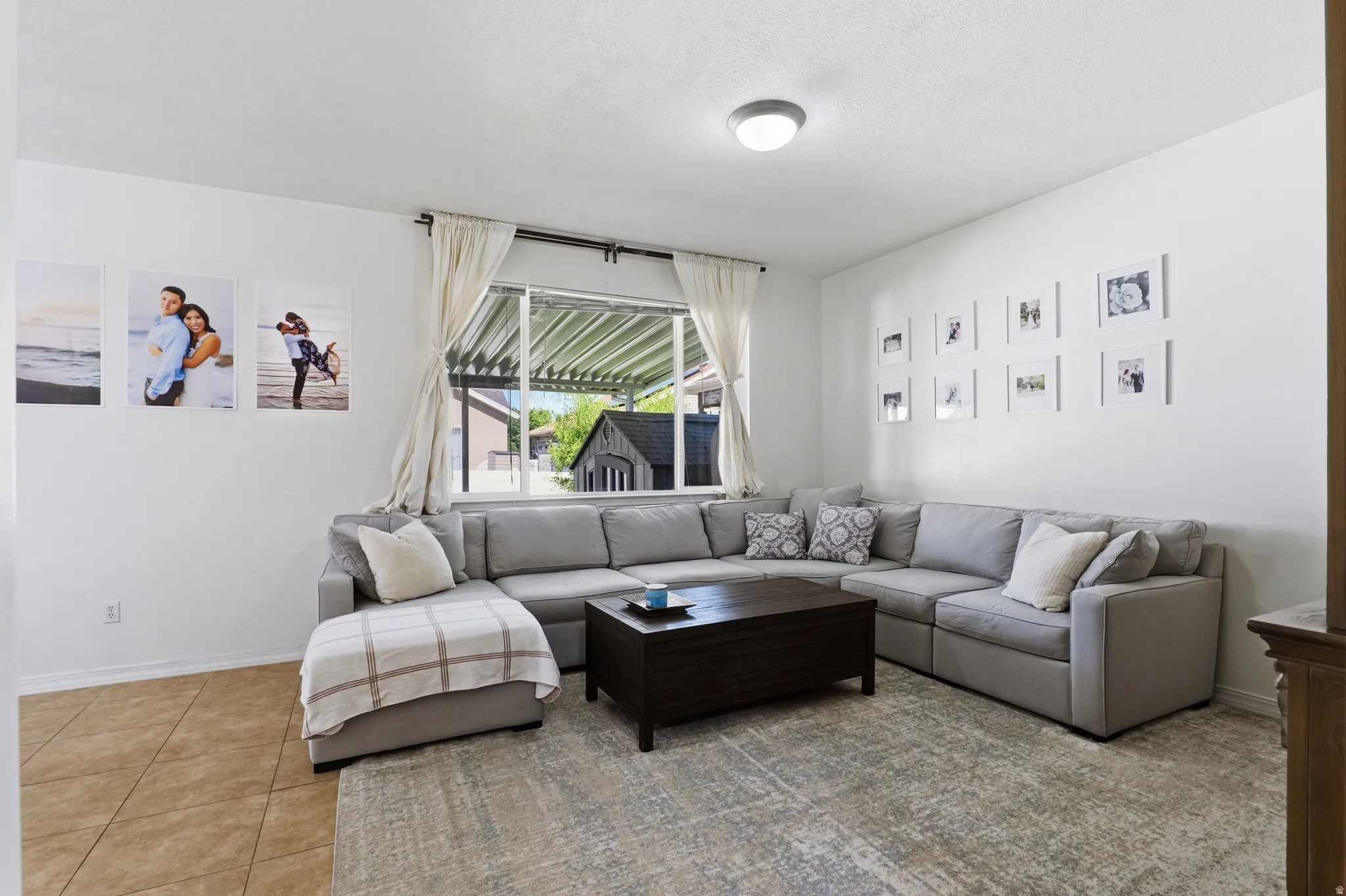 Bright living space with large window, tile flooring, and overhead lighting