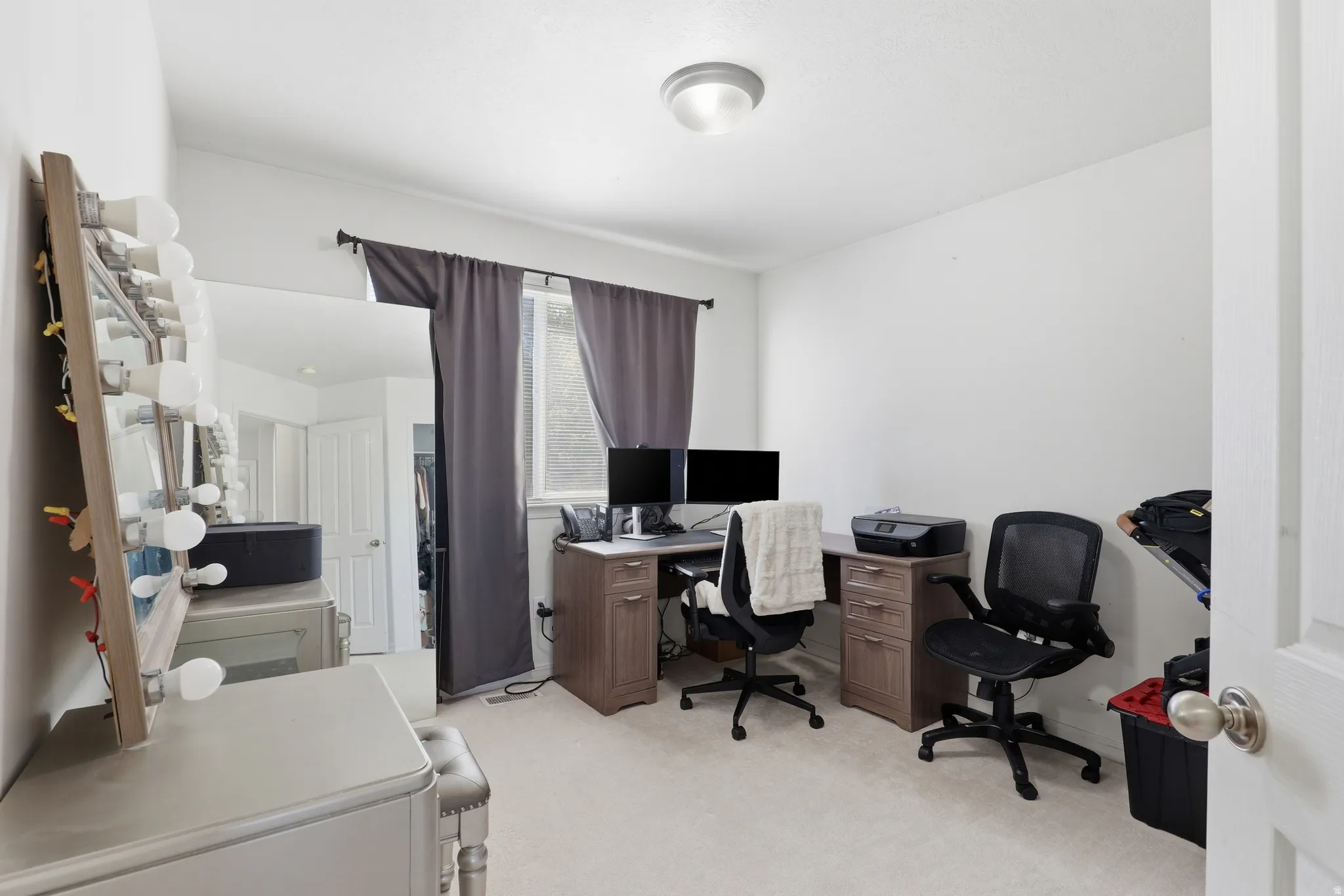 Carpeted room featuring a ceiling-mounted light fixture, a window with dark curtains, and white walls