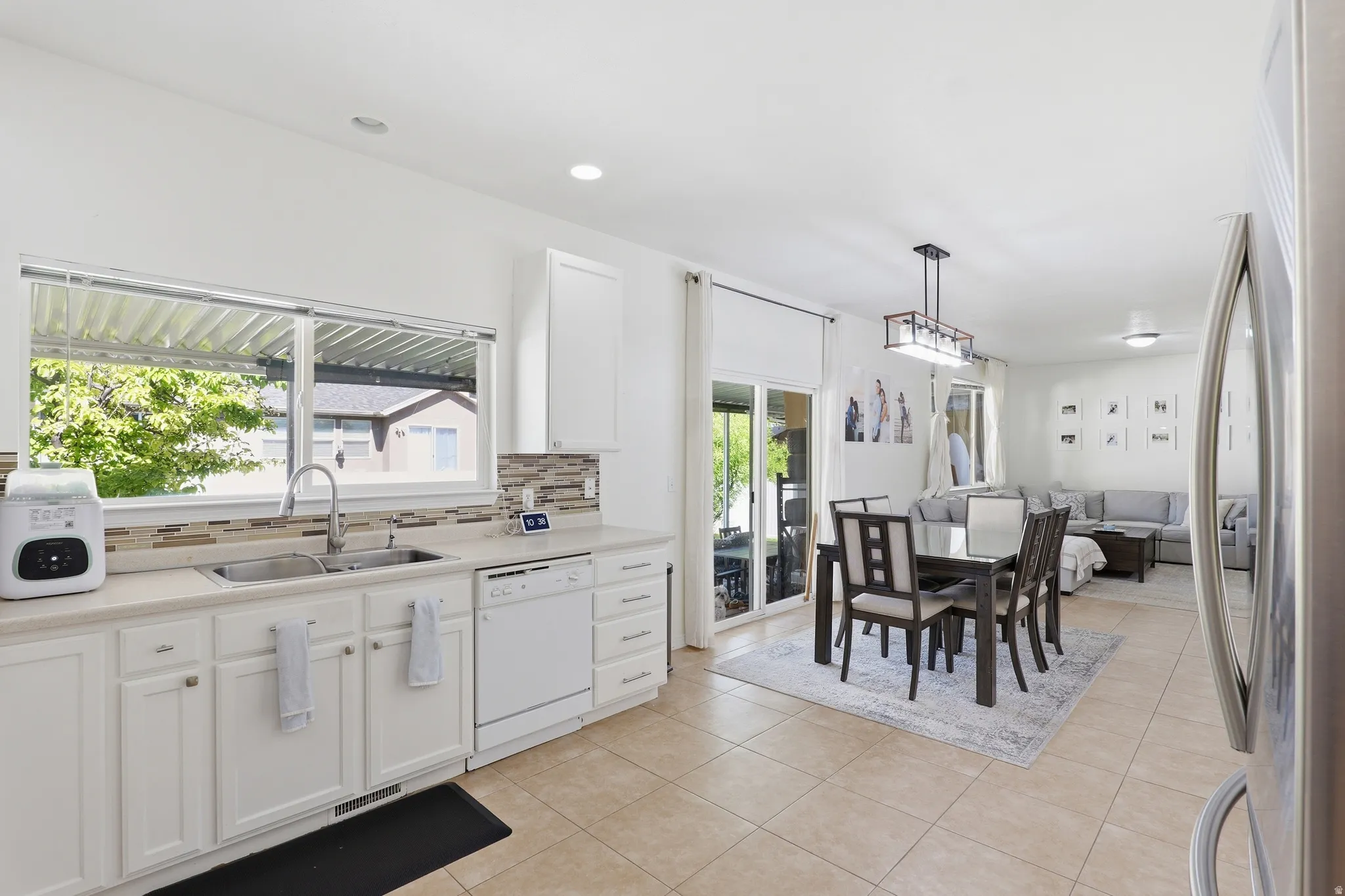 Kitchen featuring a double basin stainless steel sink, white cabinetry, and a tile backsplash