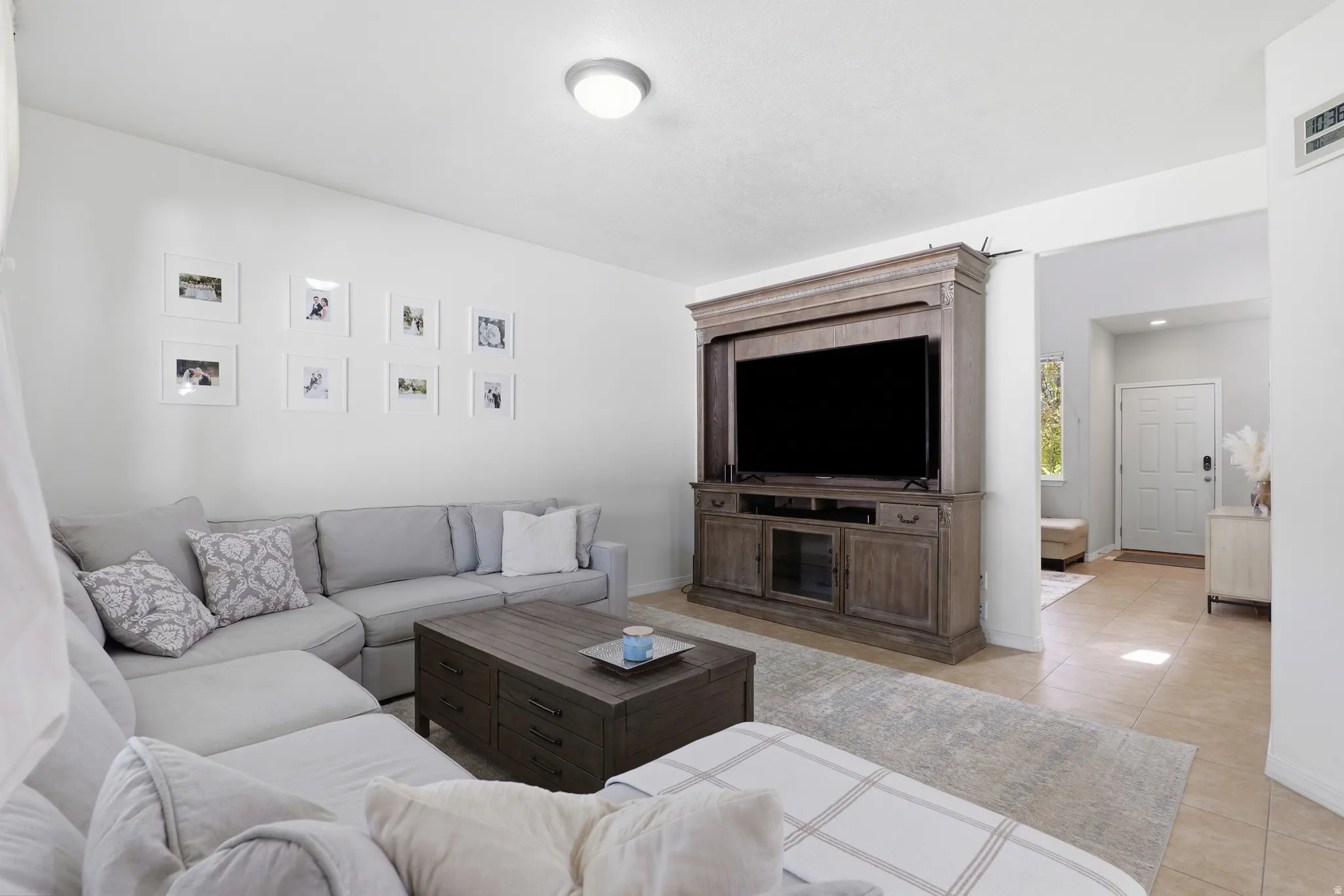 Open concept living space featuring light neutral wall tones, recessed ceiling lighting, and tile flooring