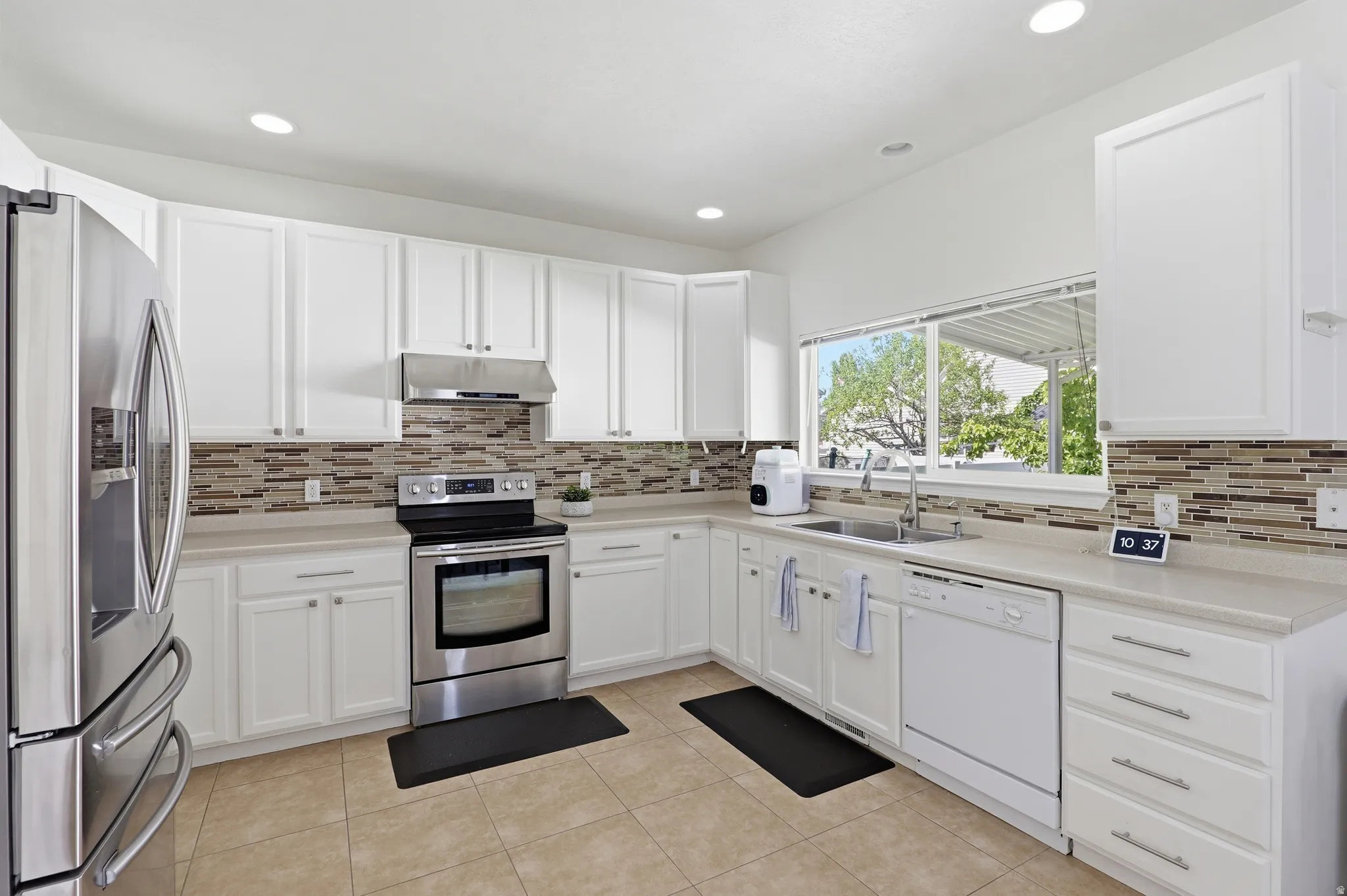 Bright kitchen featuring white cabinetry, light countertops, and a full suite of stainless steel appliances