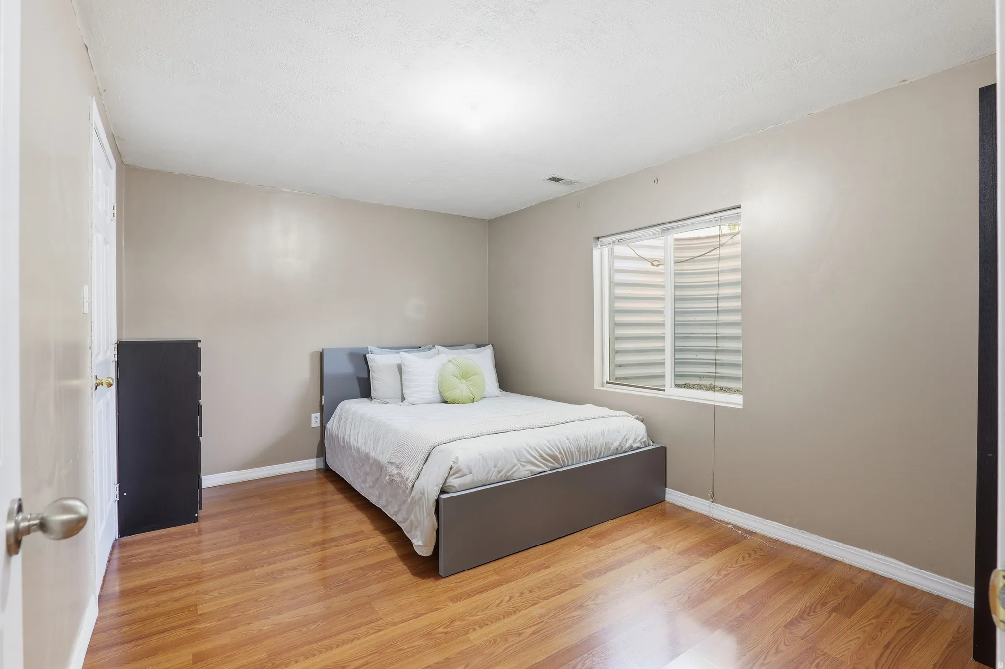 Interior room featuring wood-finish flooring, neutral wall tones, and a window with blinds