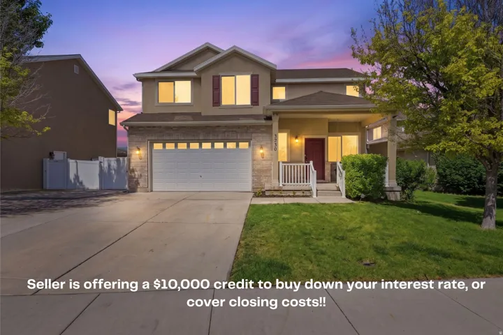 Two-Story residence featuring a covered front porch, an attached two-car garage, stone veneer accents, a red entry door and a concrete driveway.
