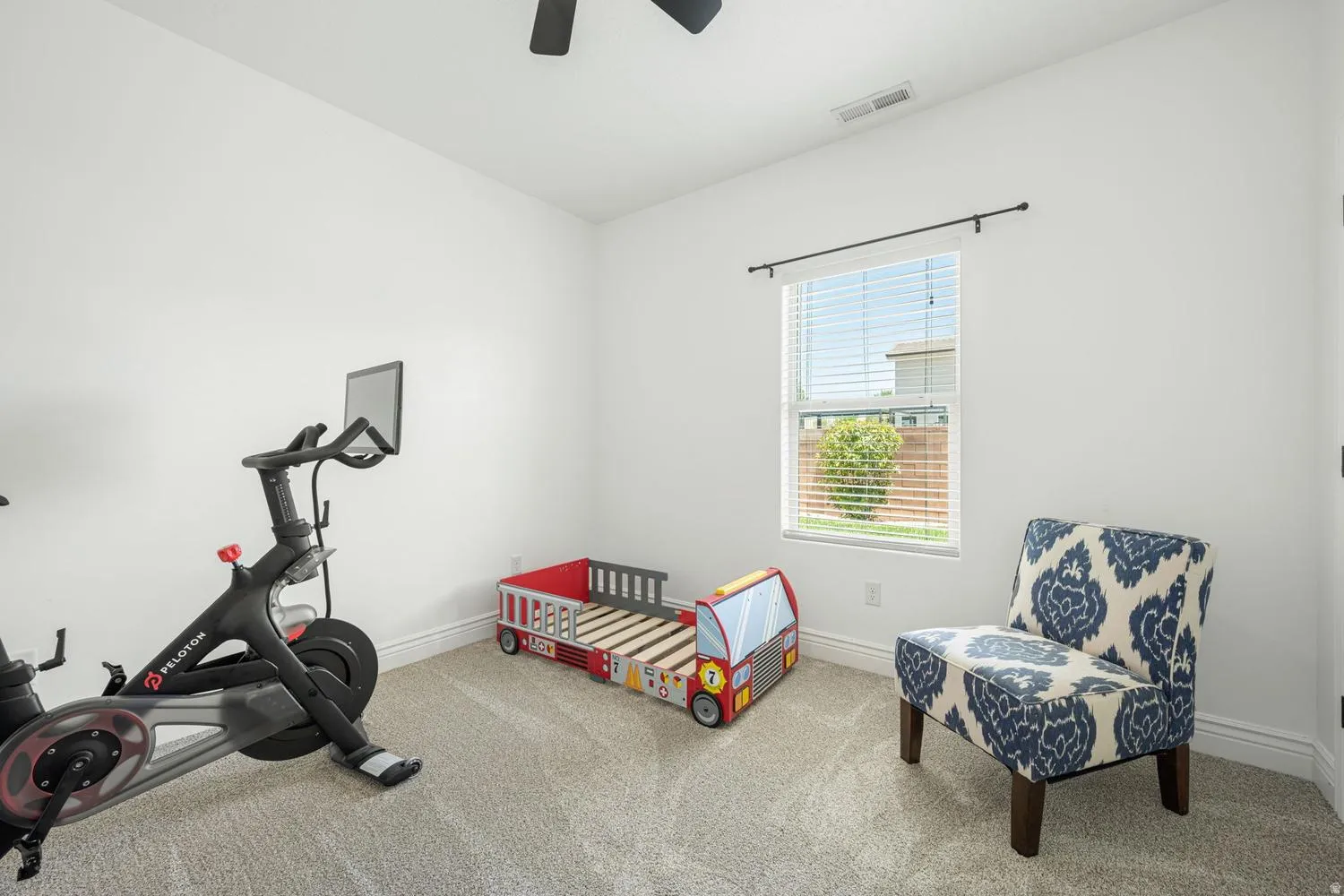 Bright room with light grey carpeting, white walls, a single window with blinds, and white baseboards