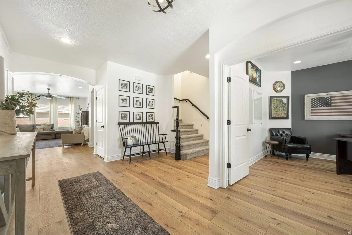 Open-concept entryway featuring wood-finish flooring, a white archway leading to a living area, and a staircase with carpeted treads
