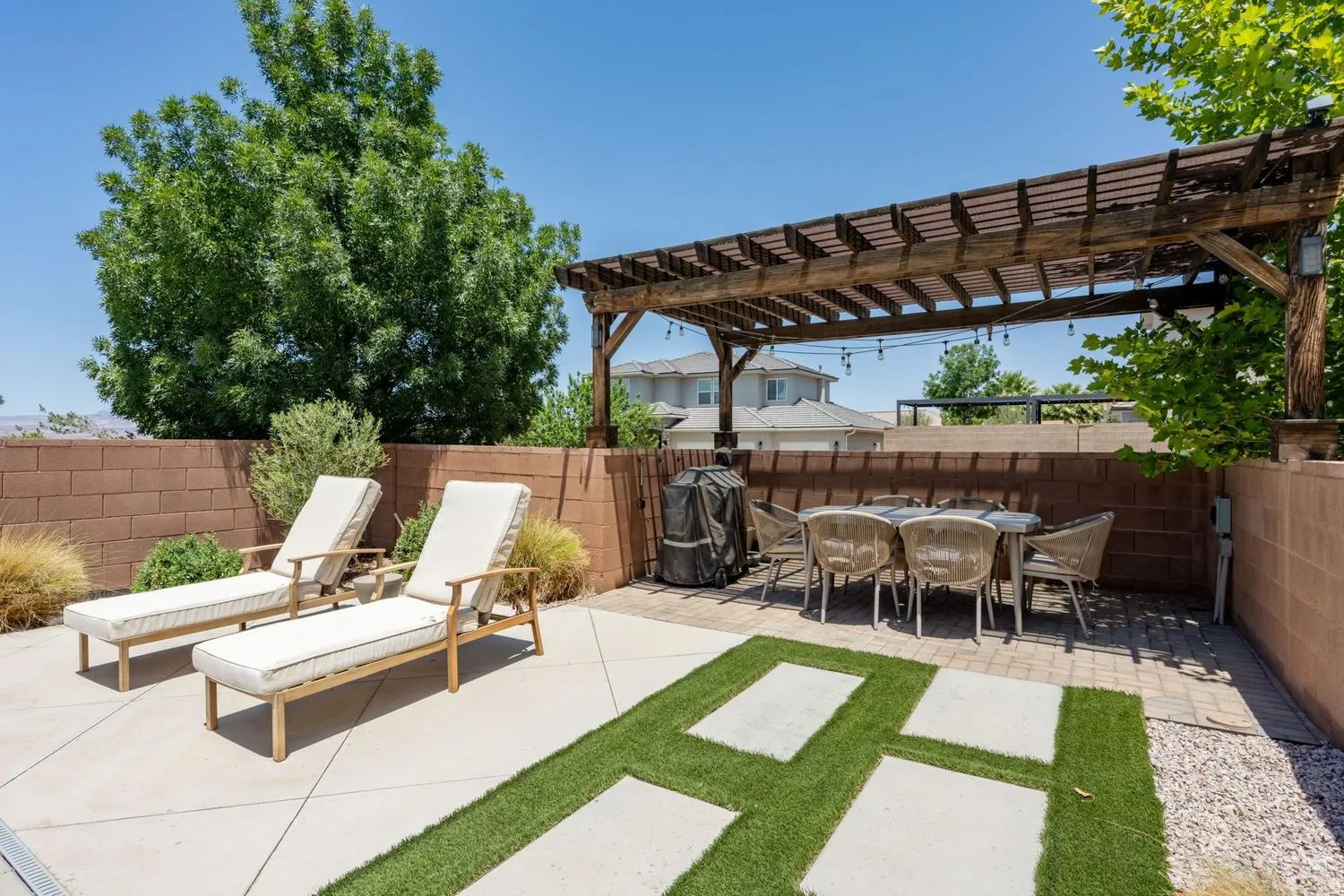 Expansive outdoor patio featuring a wooden pergola, concrete slab patio, and block retaining walls