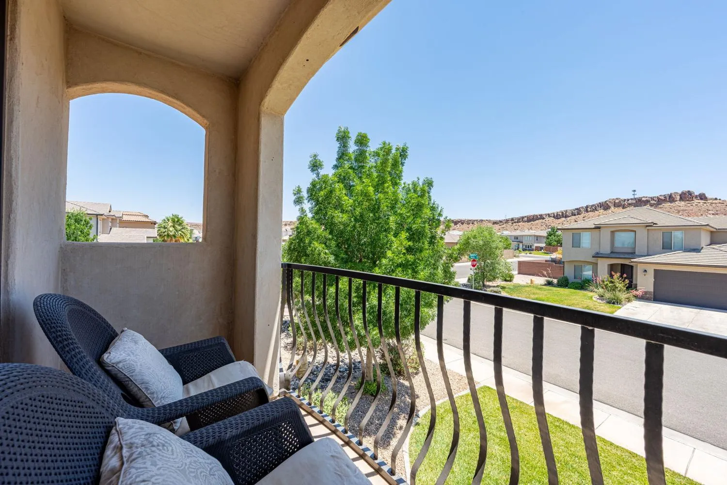 Covered balcony featuring arched architectural elements, a wrought iron railing, and stucco exterior finishes