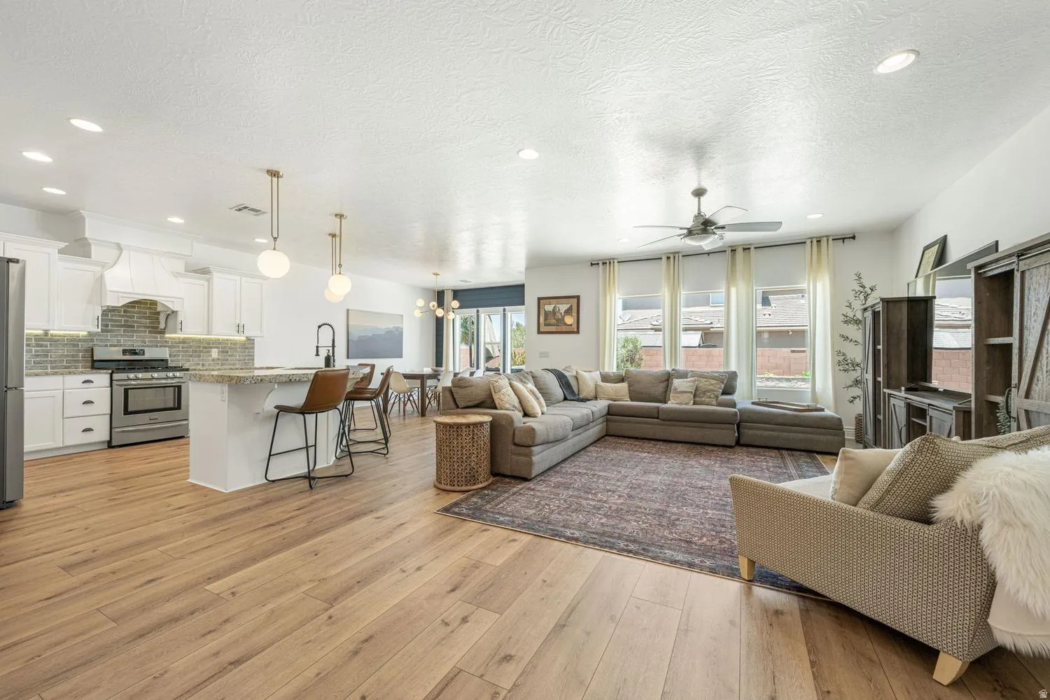 Open-concept living space featuring wood-finish flooring, recessed lighting, and a ceiling fan