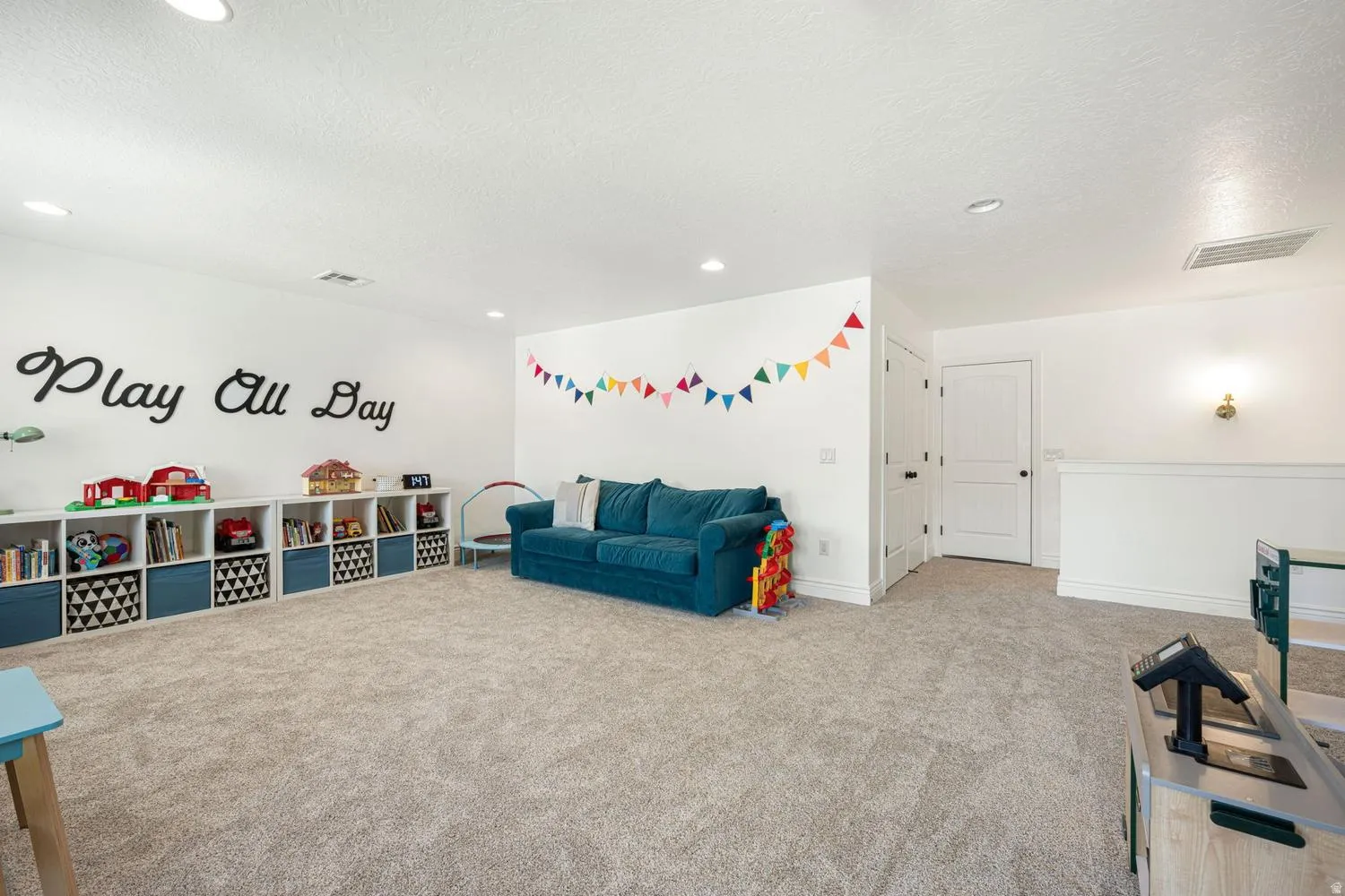 Spacious carpeted room featuring white walls and recessed lighting