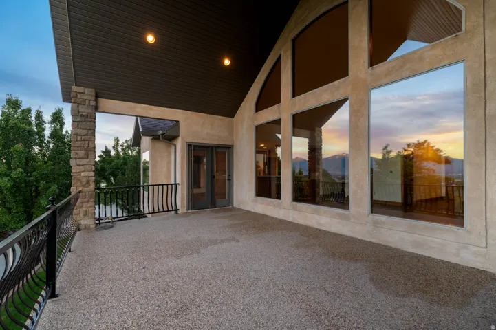 Spacious balcony  from main living room featuring a textured aggregate surface, black wrought iron railing, and a stone pillar