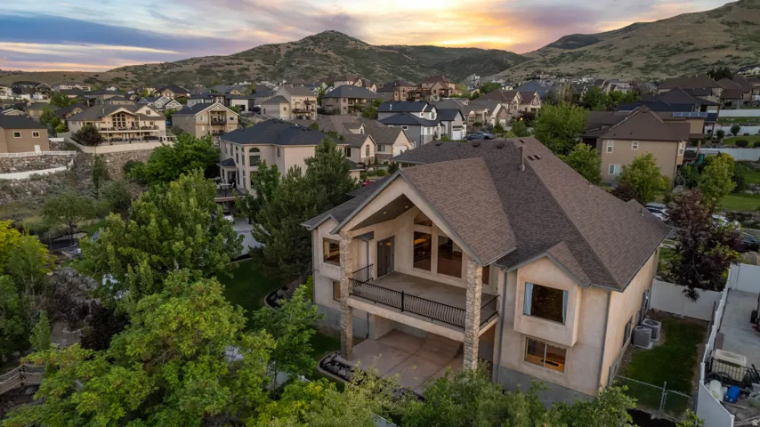 Two-story residence featuring a prominent balcony with iron railing, stucco exterior, and a multi-pitched roofline