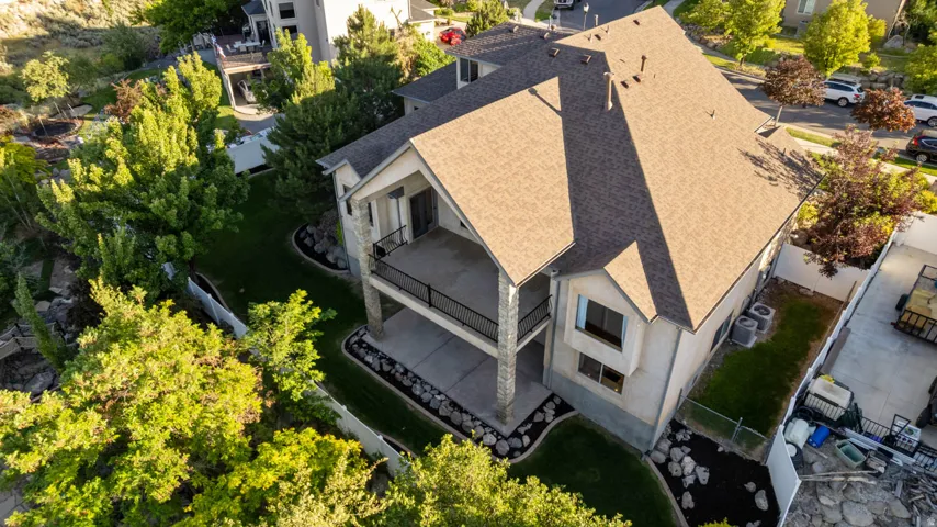 Multi-story residence featuring a stone-clad lower level and an upper-level balcony with black railings