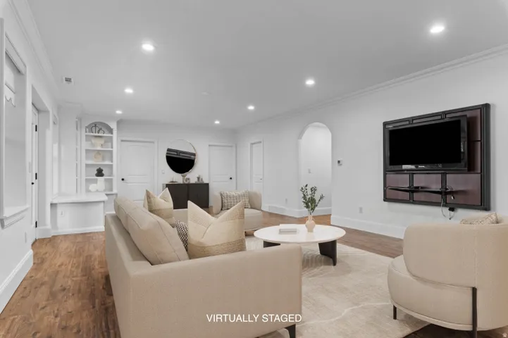 *Virtually Staged Image*  Spacious living area featuring wood-finish flooring, recessed lighting, and crown molding