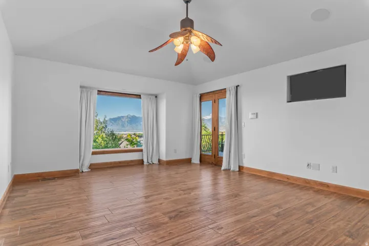 Spacious primary bedroom featuring wood-finish flooring, a vaulted ceiling, and a decorative ceiling fan