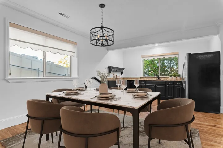 *Virtually Staged Image*  Dining area featuring a contemporary chandelier, crown molding, and wood-finish flooring