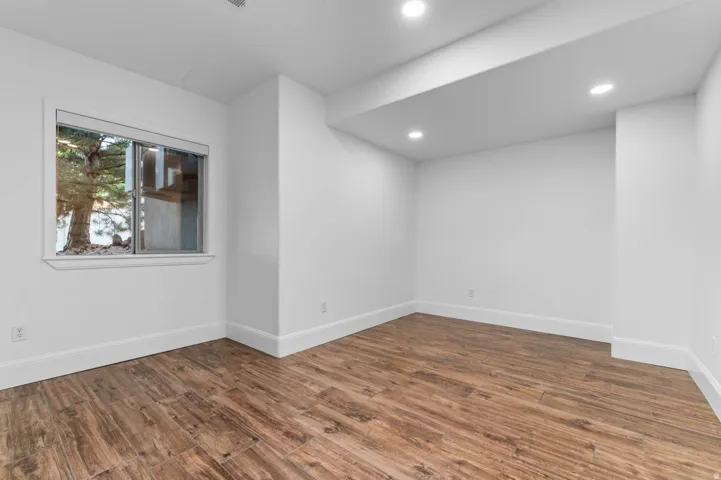 Bright room featuring wood-finish flooring, recessed lighting, and a window with a tree-lined exterior