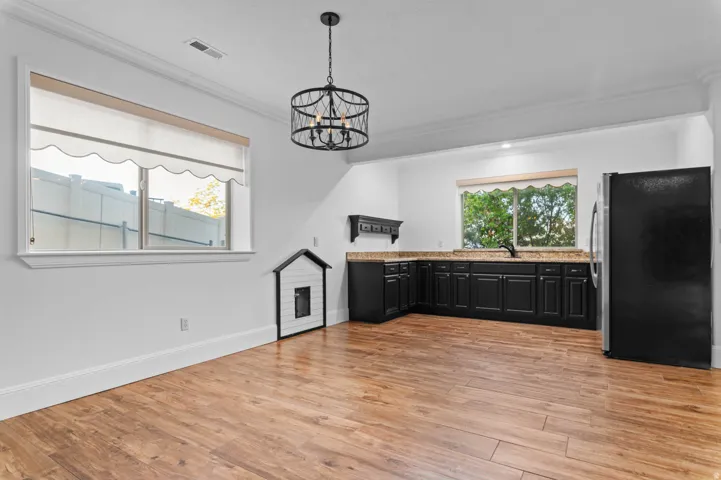 Spacious room featuring wood-finish flooring, a contemporary black chandelier, and white crown molding