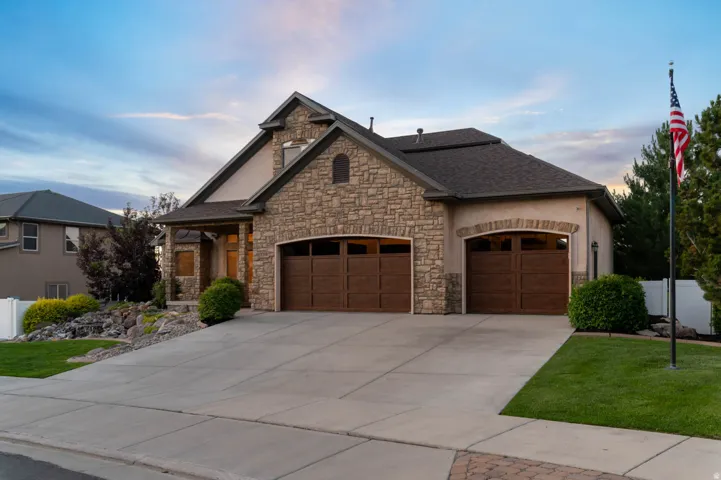 Stucco and stone exterior featuring a dark asphalt shingle roof