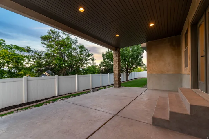 Spacious covered patio with recessed lighting and a textured concrete surface