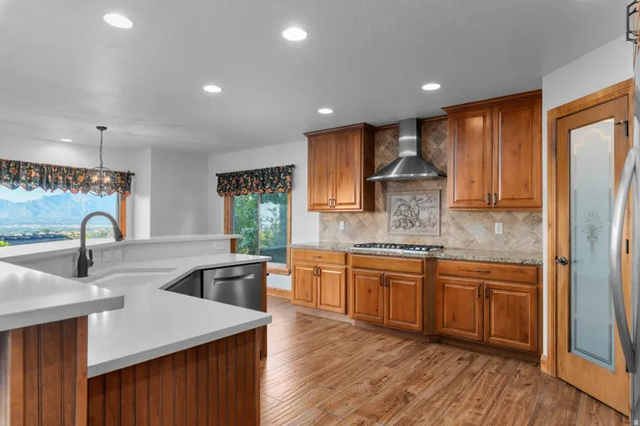 Open-concept kitchen featuring wood-finish flooring, light-toned countertops, and warm-toned cabinetry