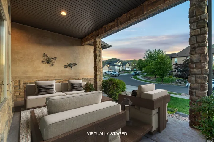 *Virtually Staged Image* Covered front porch featuring stone columns, stucco exterior with stone accents, recessed lighting, and a view of the street