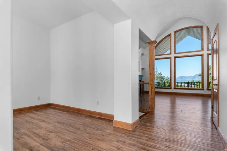 Vaulted ceilings with an arched entryway, large picture windows with arch details, wood-finish flooring, white walls, and a mountain backdrop. Amazing valley and mountain views