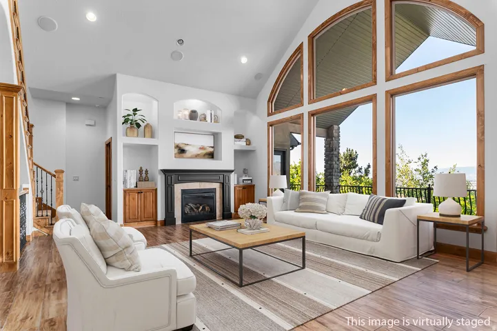 *Virtually Staged Image* Great room featuring a fireplace with a black mantel and stone surround, built-in display niches, and wood-finish flooring