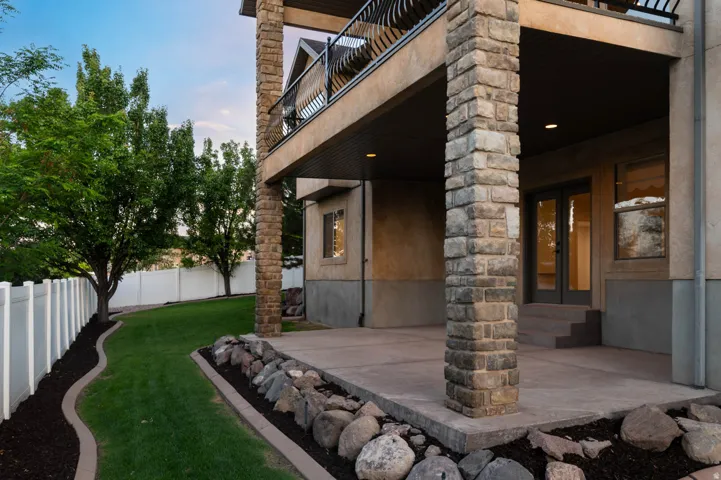 Expansive covered patio featuring stone-clad columns, concrete flooring, and recessed lighting