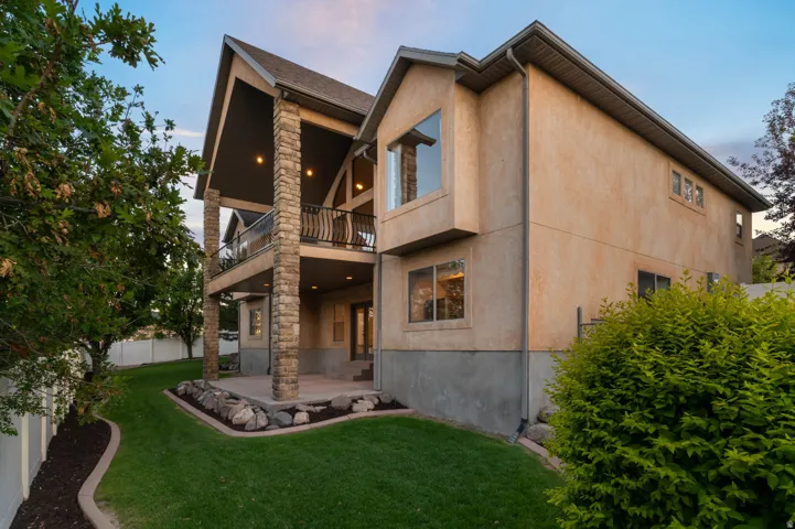 Stucco exterior residence featuring a multi-level design with stone-clad columns supporting an upper balcony