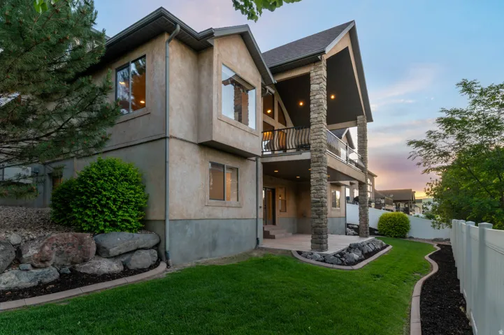 Stucco exterior residence featuring a multi-level design with a covered balcony and a ground-level patio