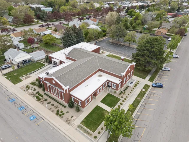 Brick exterior with white trim, multiple rooflines, and a paved parking area.
