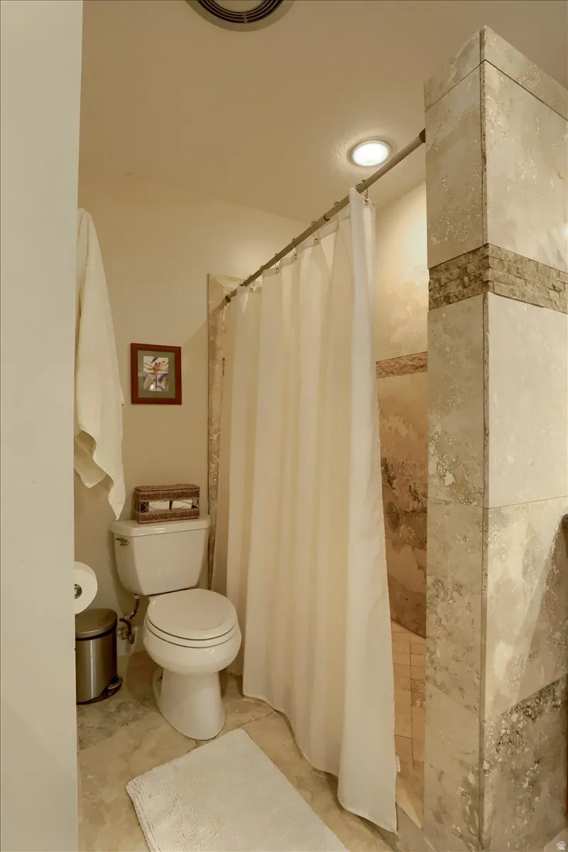 Shower with natural stone tile surround and a tiled floor