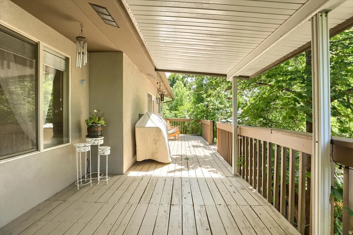 Expansive covered deck featuring wood-finish flooring, a wood railing, and a slatted ceiling