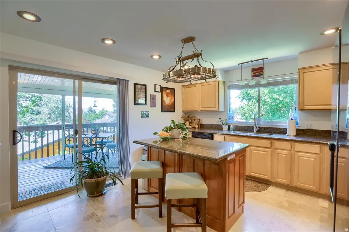 Kitchen with a central island featuring a granite countertop, light wood cabinetry, recessed lighting, a built-in dishwasher, and wood-finish flooring