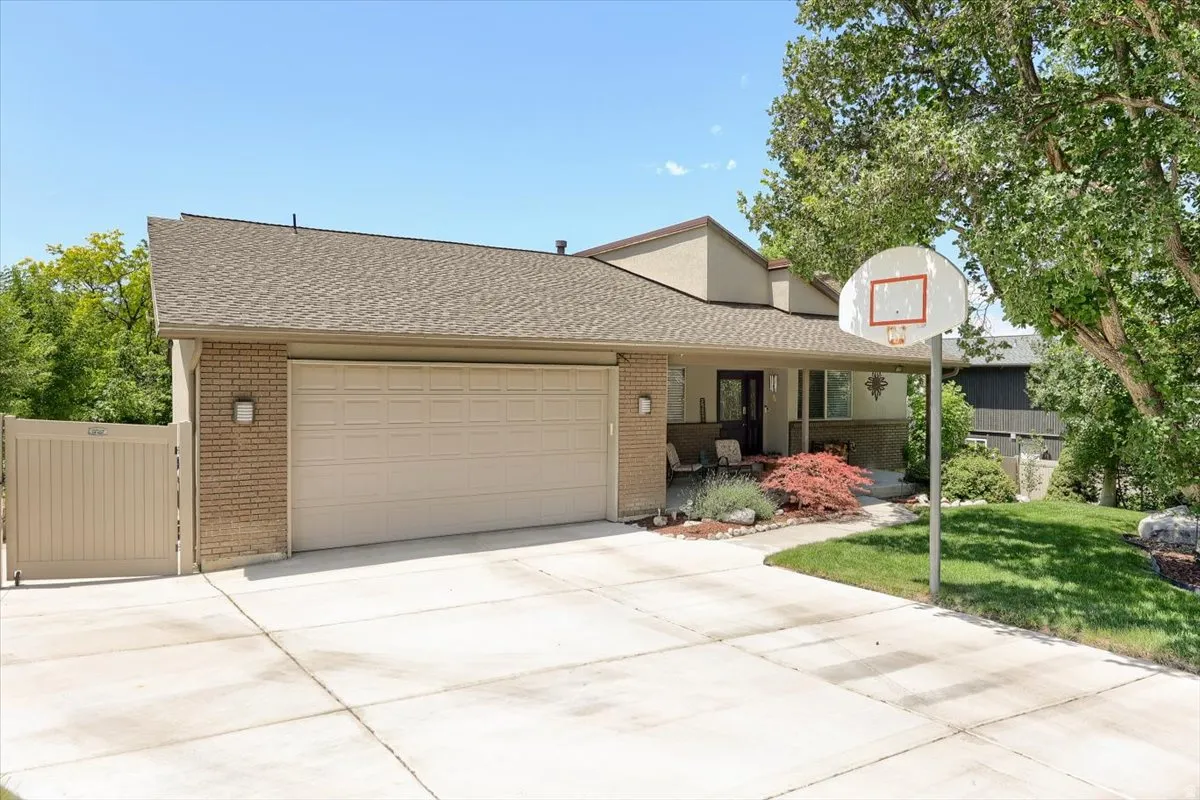 Brick facade residential architecture with an attached two-car garage, concrete driveway, front porch, and mature landscaping