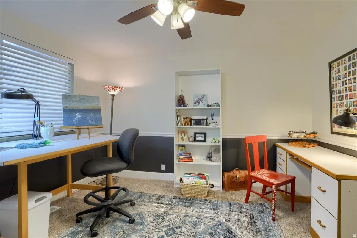 Carpeted room with a two-tone wall treatment and a ceiling fan with light fixture