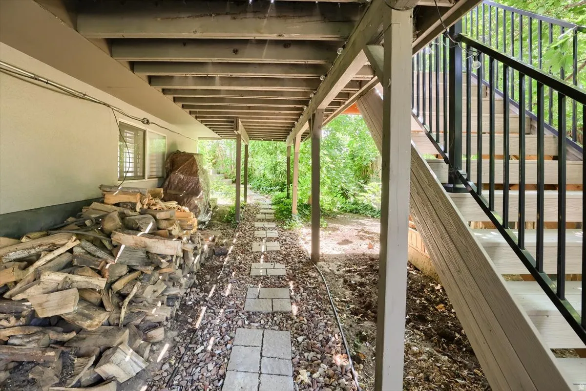 Under-deck area featuring a stone pathway, gravel ground cover, and a finished exterior wall