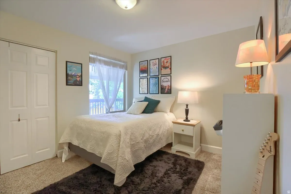 Carpeted room featuring a window with natural light, bi-fold closet doors, a ceiling-mounted light fixture, and neutral wall tones