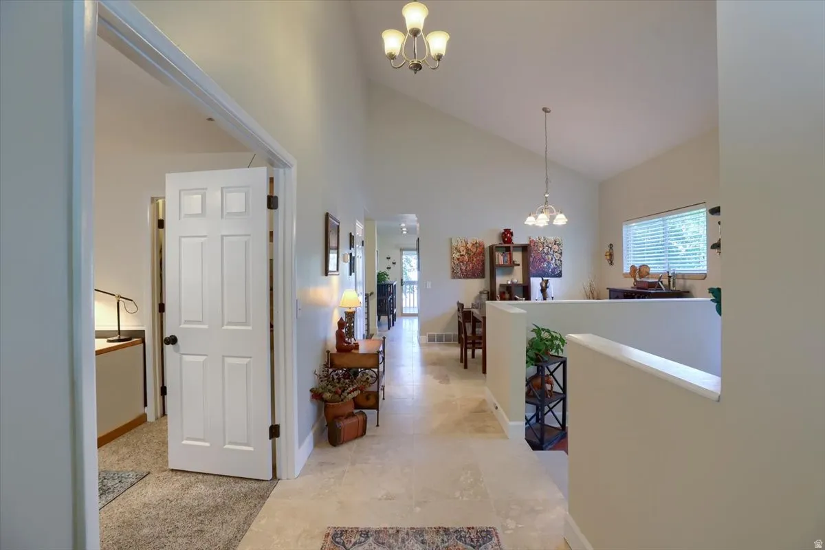 Vaulted ceilings and recessed lighting complement the tile flooring throughout the main hallway