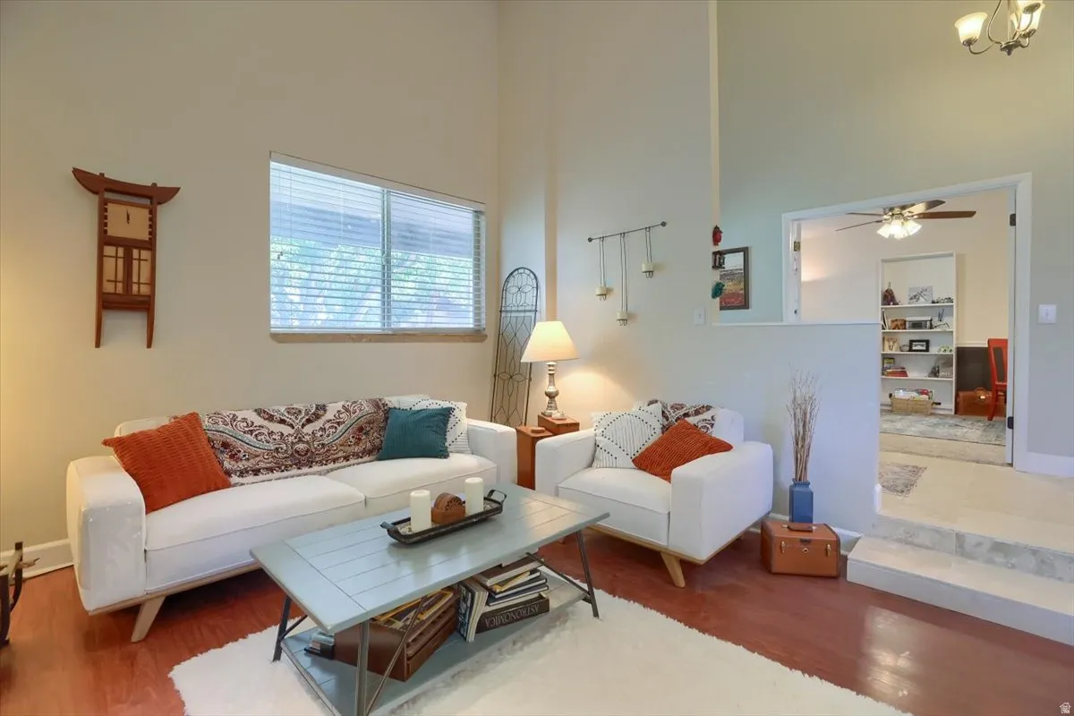 Living area featuring high vaulted ceilings, wood-finish flooring, and a large window with blinds