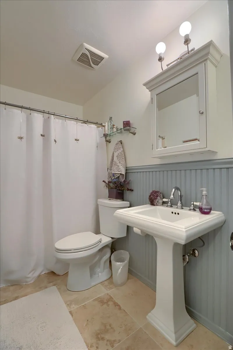 Pedestal sink with chrome faucet, complemented by a white medicine cabinet with integrated lighting
